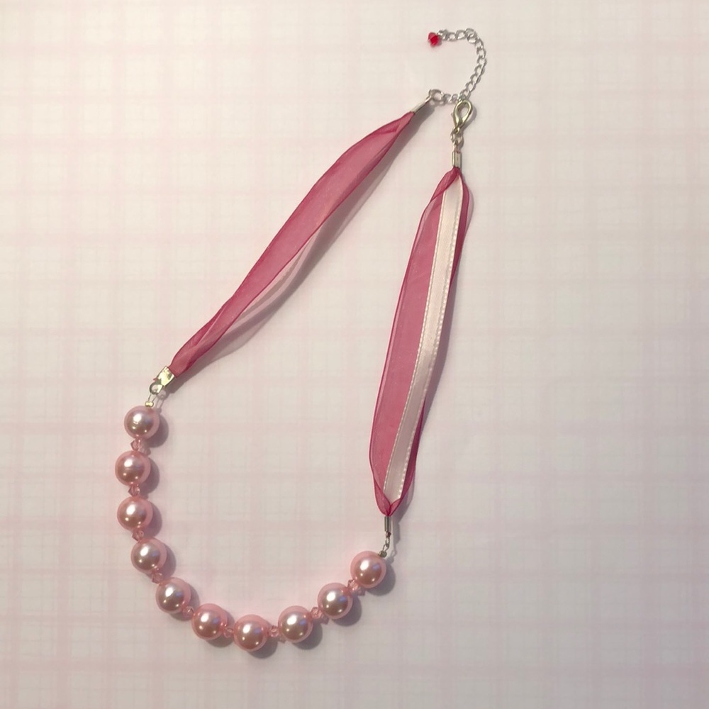 Pink pearl necklace with ribbon chain.